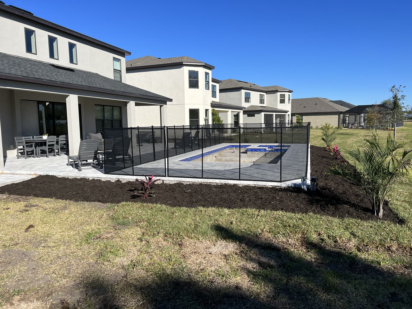 After — North Port backyard — bare lot transformed into a landscaped pool deck with fresh sod and mulch