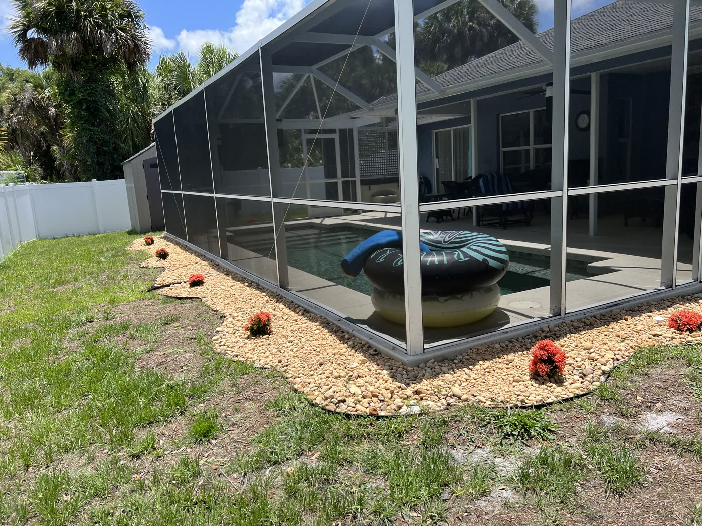 Screened pool enclosure with a new rock border and flowering plants
