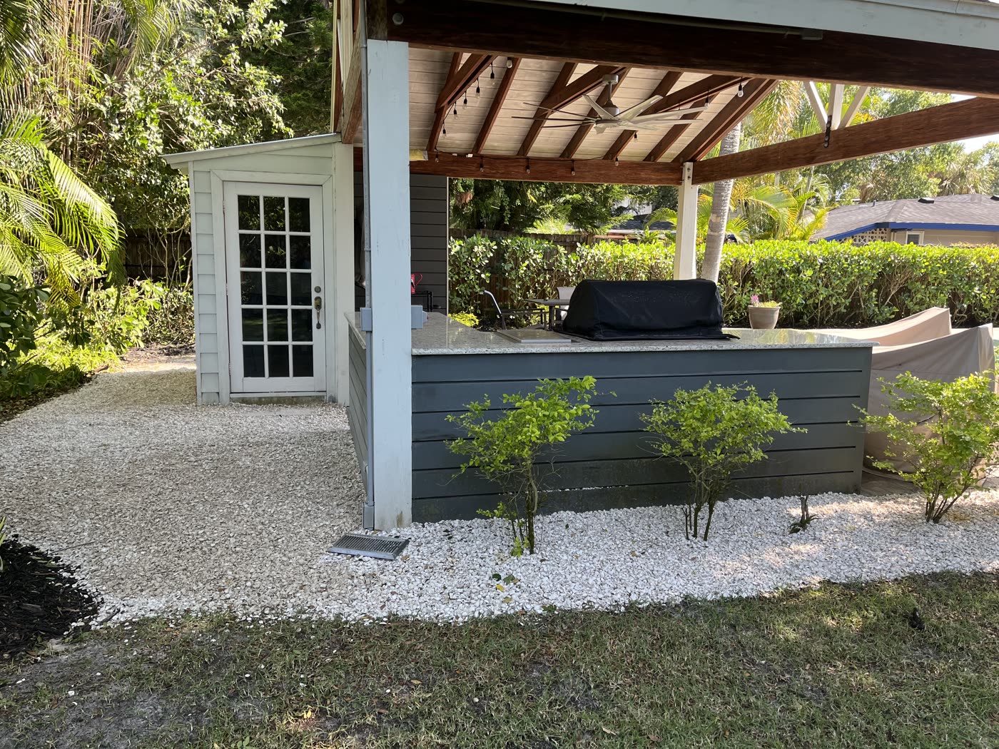 Outdoor patio pergola with white gravel and trimmed shrubs